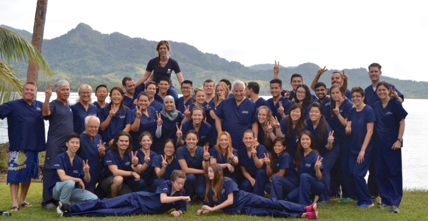 The Ayuda International dental clinic team in navy scrubs by the water at Mission Natuvu, Fiji
