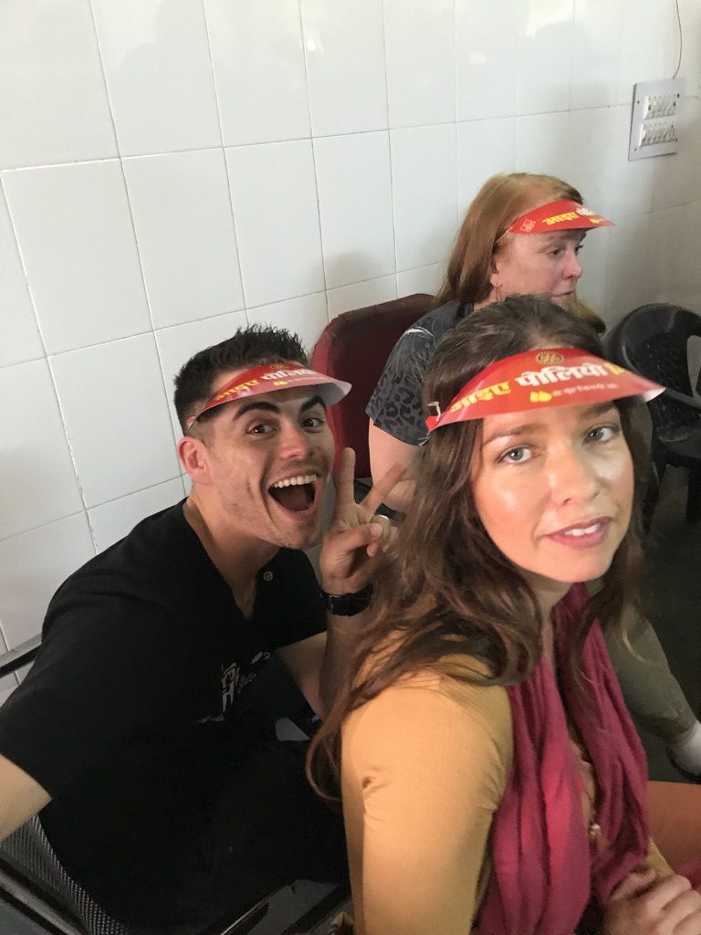Smiling volunteers wearing red paper visors on a service trip