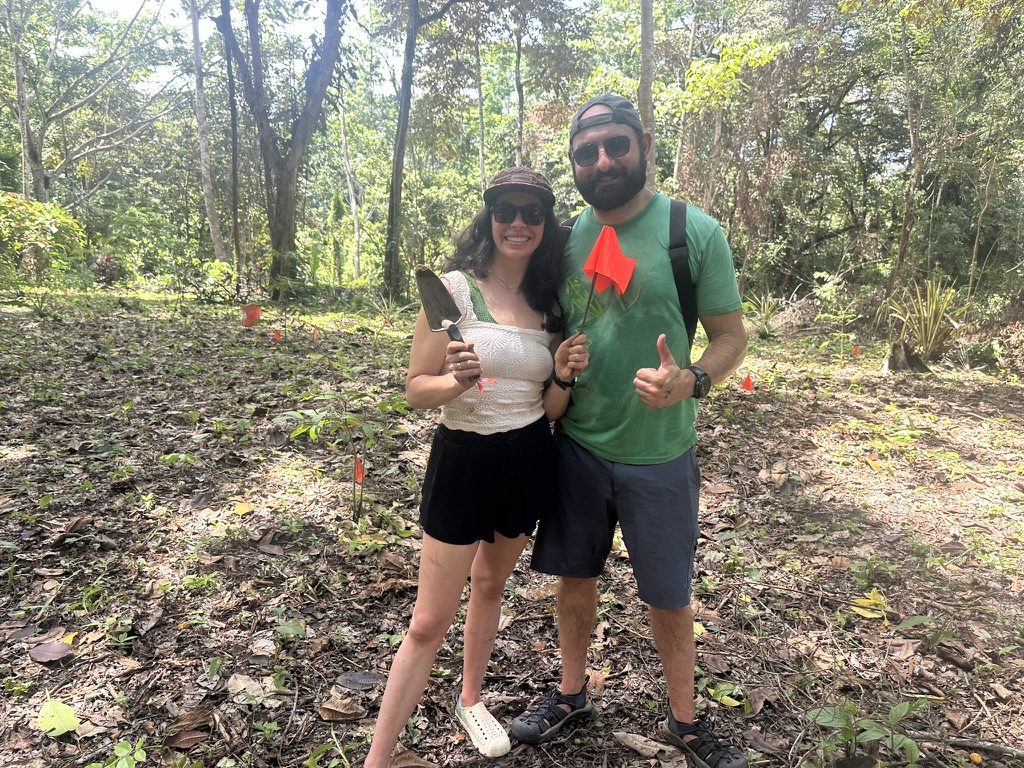 Two volunteers with a trowel and a marker flag while planting mountain almond trees in Bocas del Toro